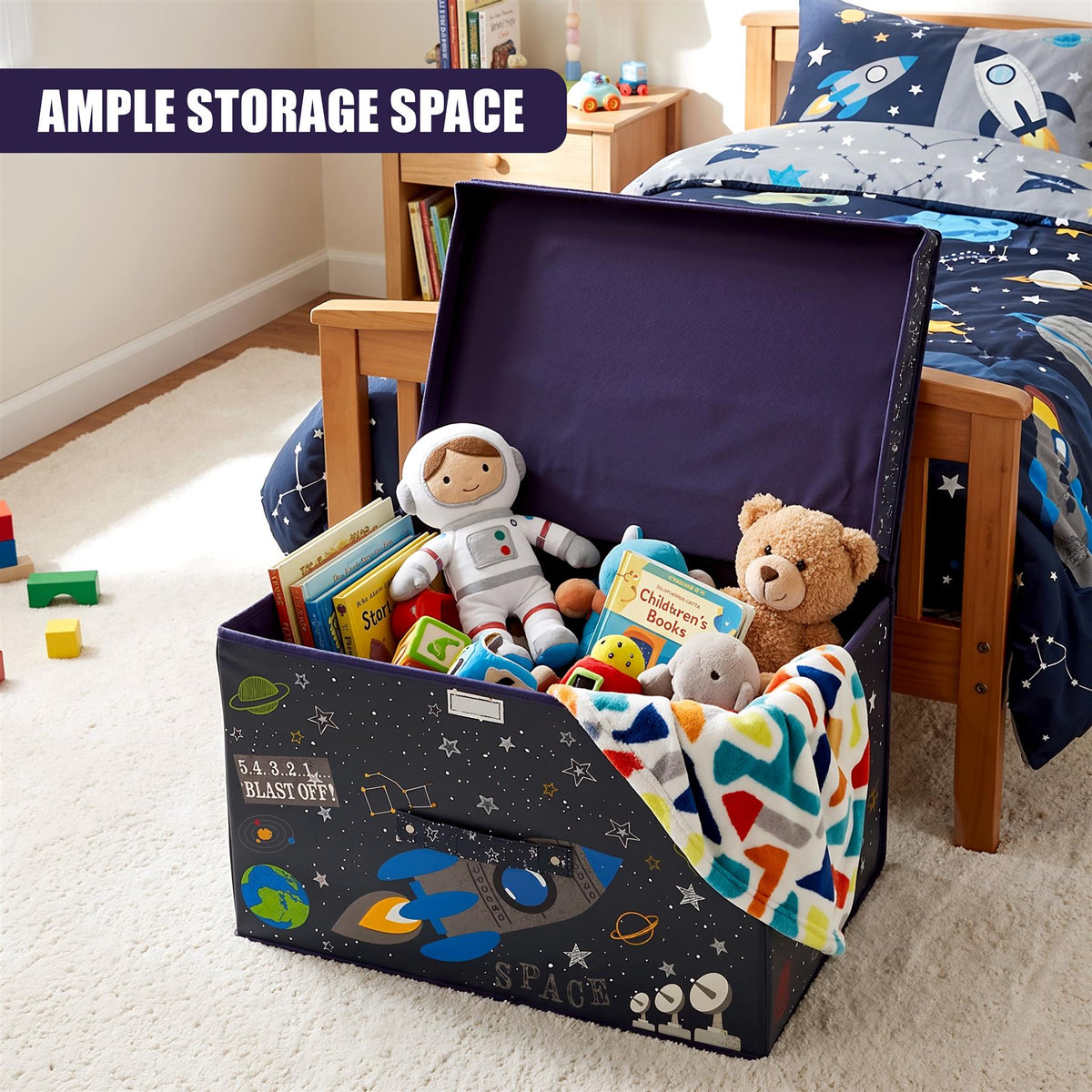 The Magic Toy Shop Blast Off Large Storage Box filled with toys and books, sitting on a carpeted floor next to a bed