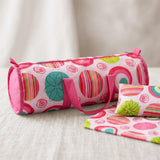 Pink and multicolor travel bag patterned with stripes, alongside two smaller matching pouches.
