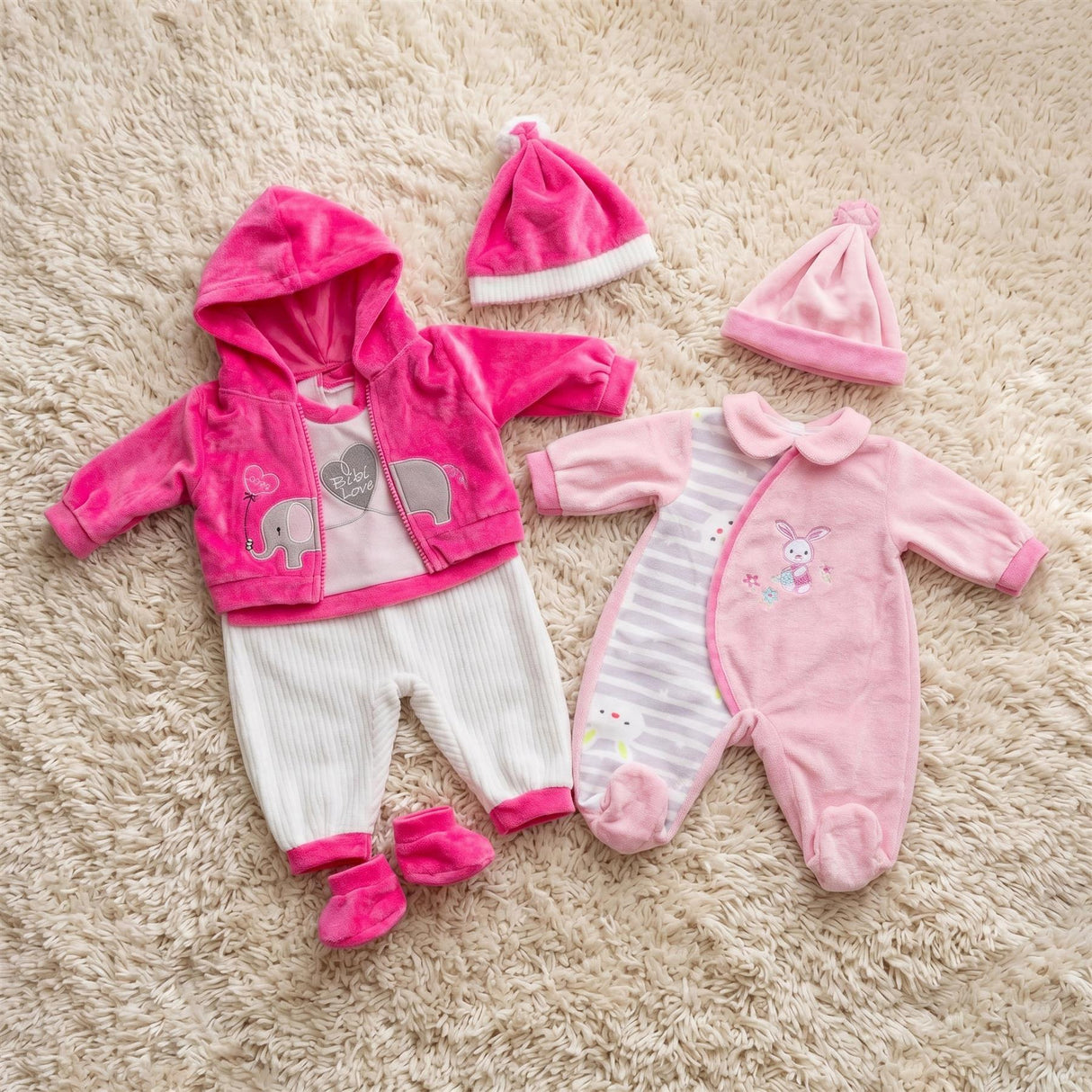 Pink and white doll outfits featuring an elephant print, a striped sleeper, and coordinating matching hats.