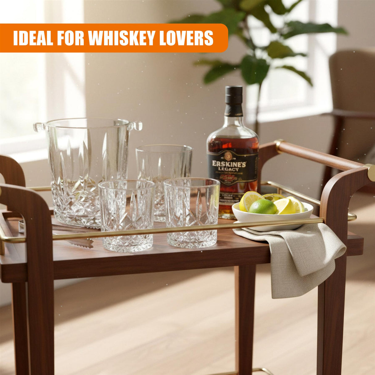 A wooden table displays an ice bucket, four whiskey glasses, a bottle of whiskey, and green apples.