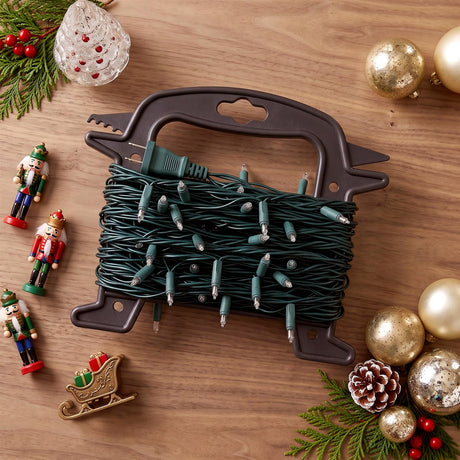 A brown plastic Christmas light reel storage unit holding green fairy lights, surrounded by festive decorations including