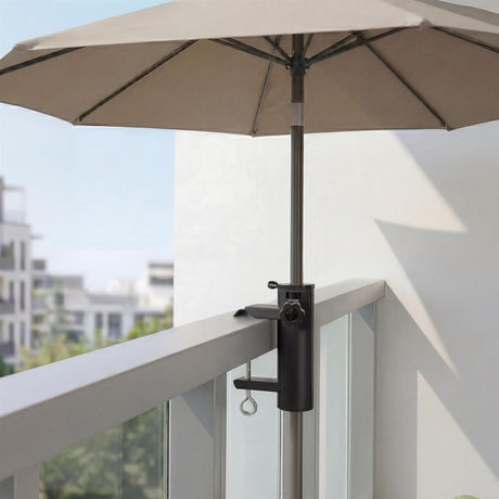 Black metal parasol clamp securing the pole to a light-colored balcony railing.