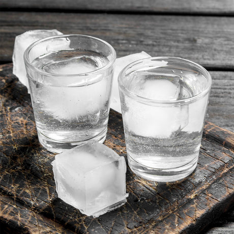 Three shot glasses with ice cubes.