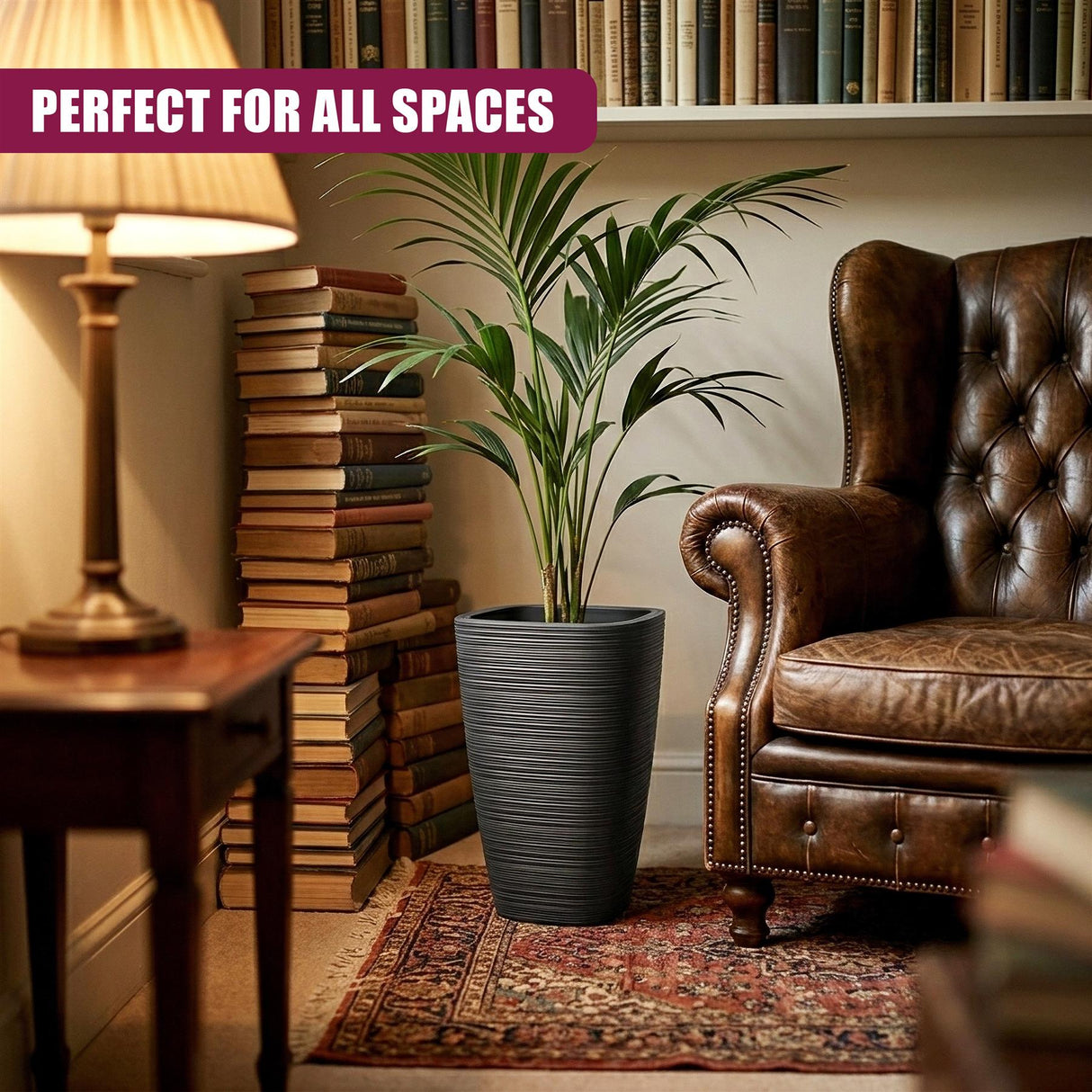 Tall, dark gray, ribbed flower pot holding lush green tropical foliage near a leather armchair.