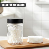 Clear glass jar holding white spice sticks rests near a stack of white round lid components on wood.