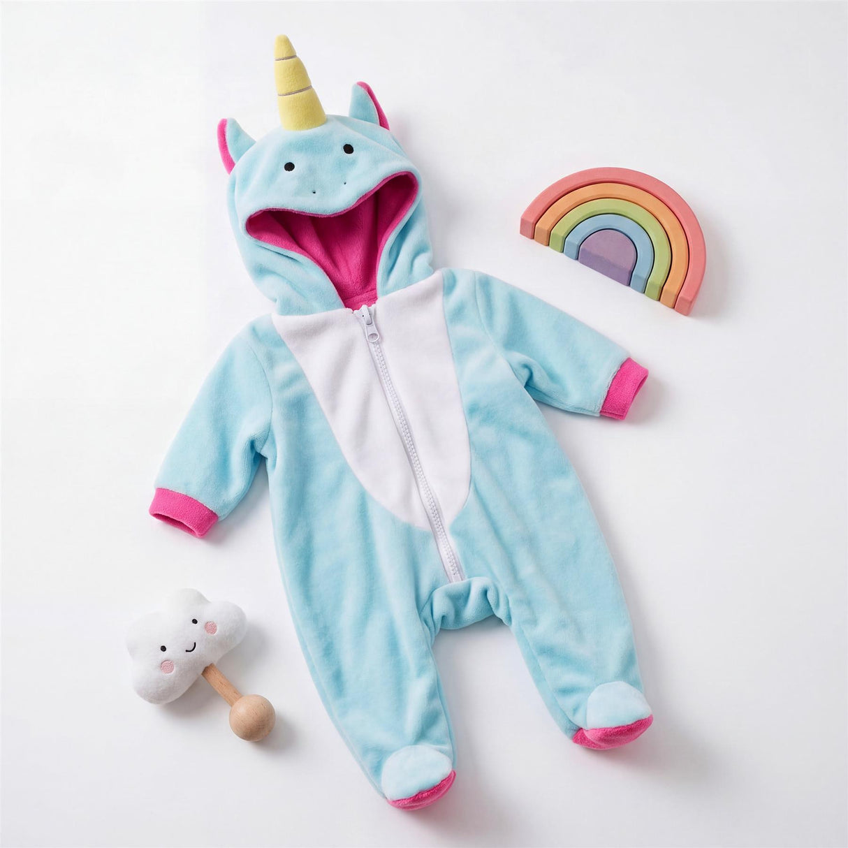 Blue unicorn hooded onesie outfit displayed alongside a cloud toy and colored rainbow arch.