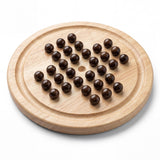 Round wooden game board featuring dark pellets arranged in a distinct pattern.