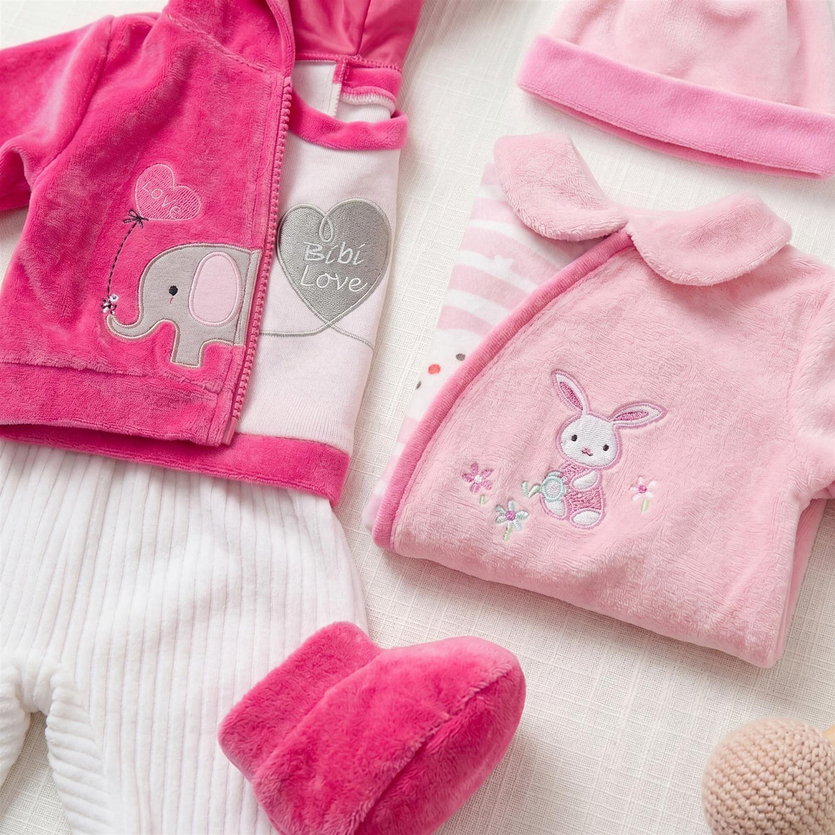 Set of plush doll clothes in pink and white, including an elephant graphic and a bunny applique.