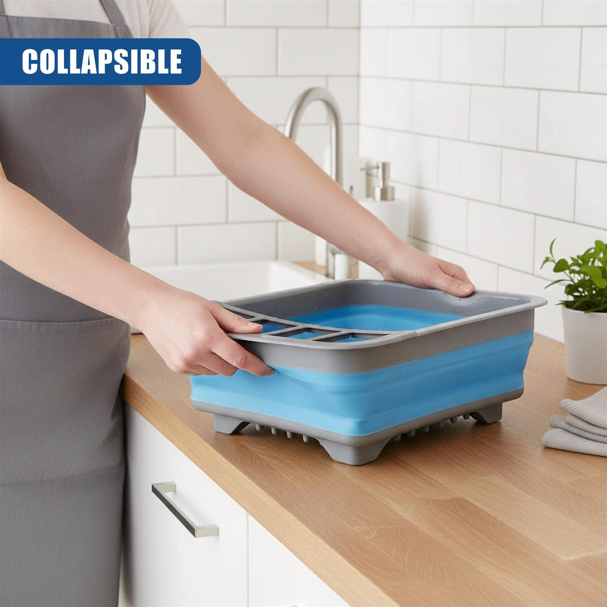 The person is handling a blue and gray two-tiered dish drainer placed on a wooden countertop.