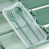 A plastic case containing two green spoons in a compartment.