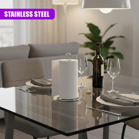Stainless steel kitchen roll stand visible on a glass dining table among plates and wine glasses.