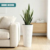 White fluted pot holding a vibrant green houseplant, featuring long, upright leaves.