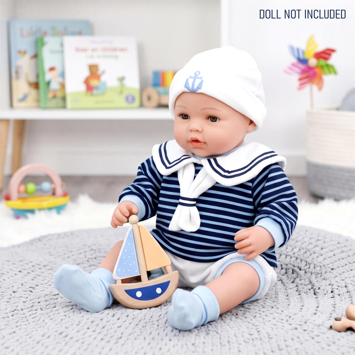 A doll dressed in a navy striped sailor outfit sits next to a wooden sailboat toy.