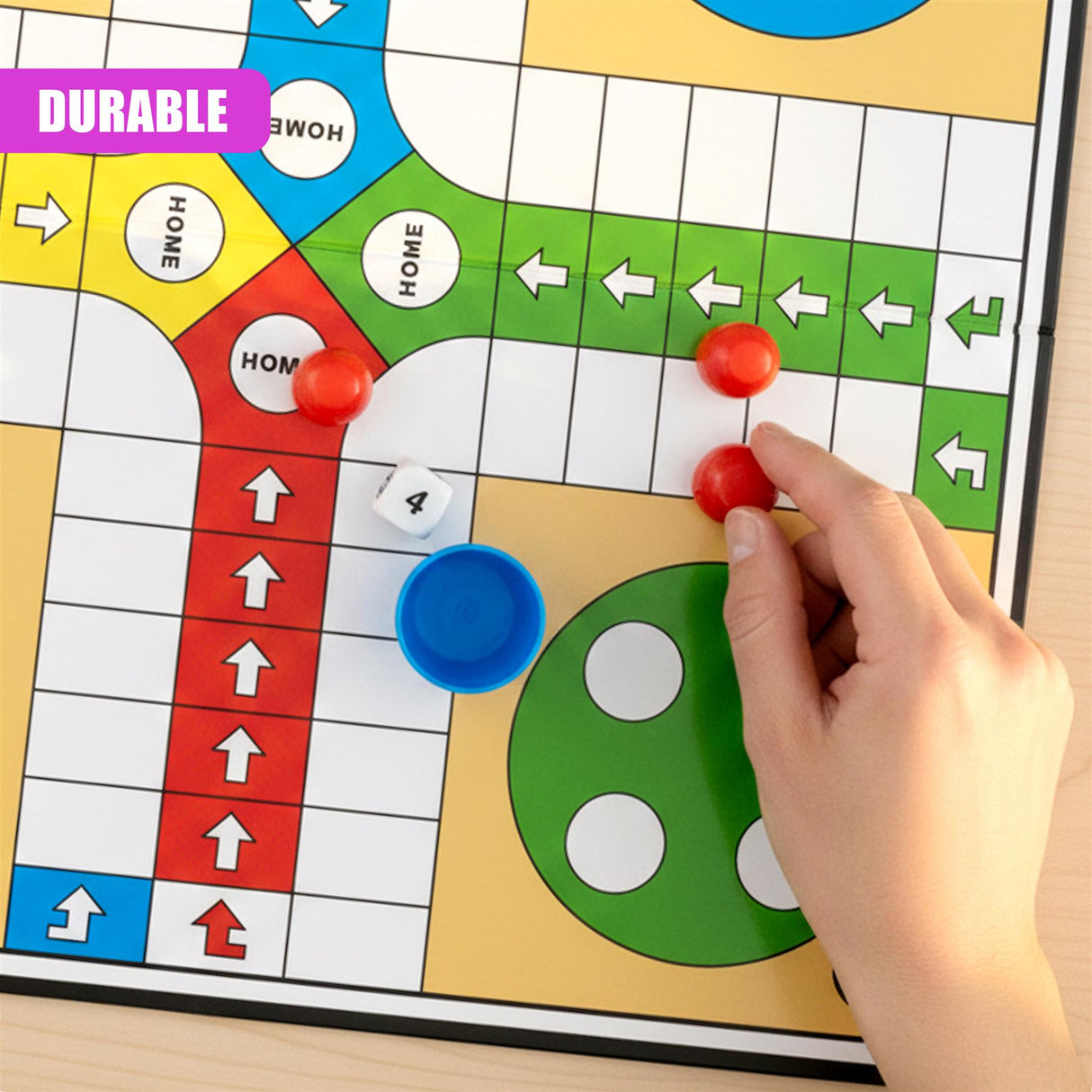 A hand places a red playing piece on the Ludo board near the central starting area.