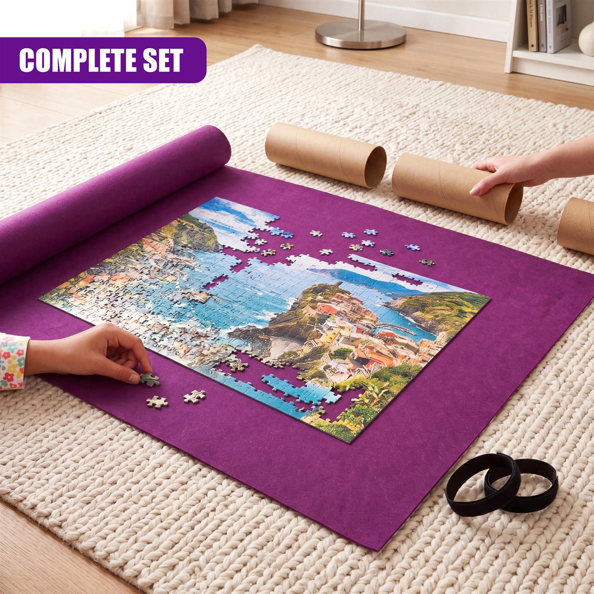 Jigsaw puzzle components are laid out on a purple mat next to rolled puzzle sections.