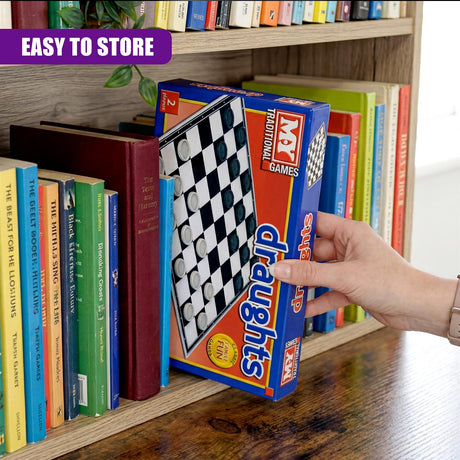 Blue and red box containing a folding draughts game sits among stacked books on a wooden surface.