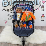 Blue twin pushchair with two dolls, one boy and one girl, sitting in the seats.