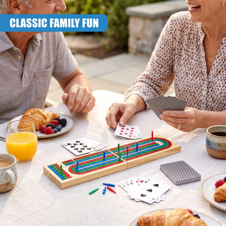 A wooden cribbage board game on a table with two smiling adults playing cards and breakfast items nearby