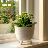White ceramic planter with textured horizontal rings and small legs, holding fresh green flowers.