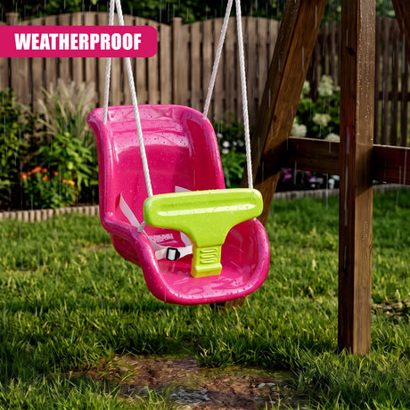 A pink toddler swing seat with a green safety bar and white ropes hanging from a wooden frame in a grassy garden during rain