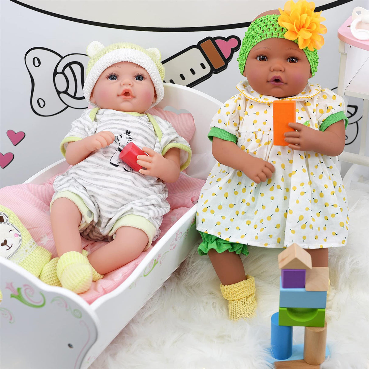 Two baby dolls pose with a white wooden cradle and a colorful wooden stacking toy structure.