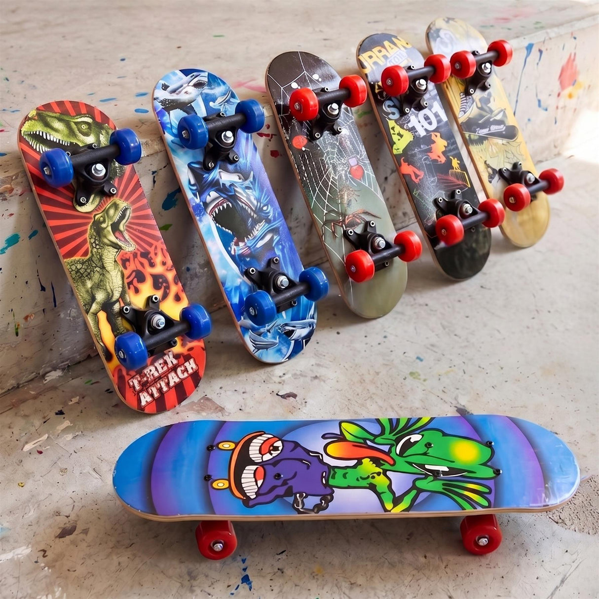 Multiple colorful skateboards featuring various graphics are displayed on a textured concrete surface.