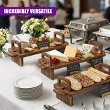 A collection of wooden serving platters displays cheeses, crackers, bread, grapes, and various fruit snacks.