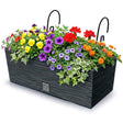 Black rectangular planter box filled with colorful flowers, greenery, and two curved hangers.