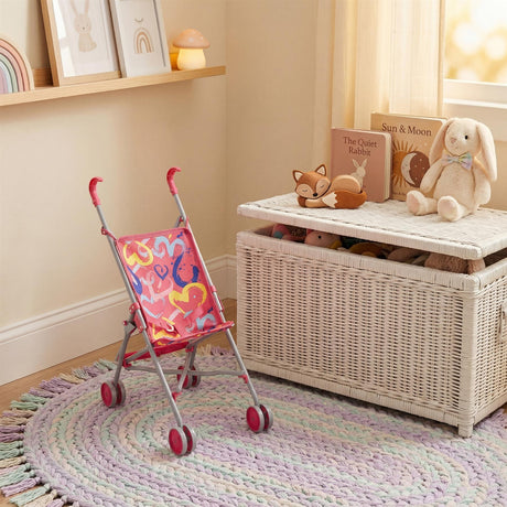 Pink patterned doll's buggy toy stroller sits on a colorful woven rug.
