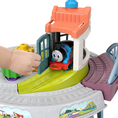 Colorful toy train set featuring a green track, blue train, orange station, and pink play area.