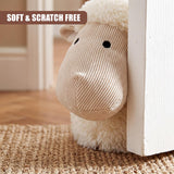 Beige sheep figure door stopper resting against a white door frame on a woven mat.