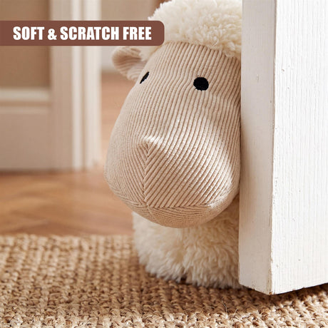 Beige sheep figure door stopper resting against a white door frame on a woven mat.