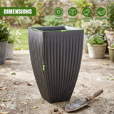 Large, dark gray planter pot with vertical ribs sits on concrete beside a garden shovel.