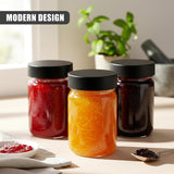 Glass spice jars filled with red, orange, and brown spices sit on a counter with foliage in the background.