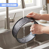 A used metal cake tin is rinsed with water in a stainless steel kitchen sink.