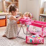 The set includes a pink toy high chair, a large cot, and a patterned pink and white travel accessory bag.