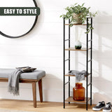 Black metal four-tier shelving unit displays decorative items, plants, and textiles.