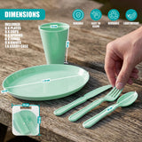 Mint green picnic utensils, plates, and cups are displayed on wood next to a rectangular storage case.