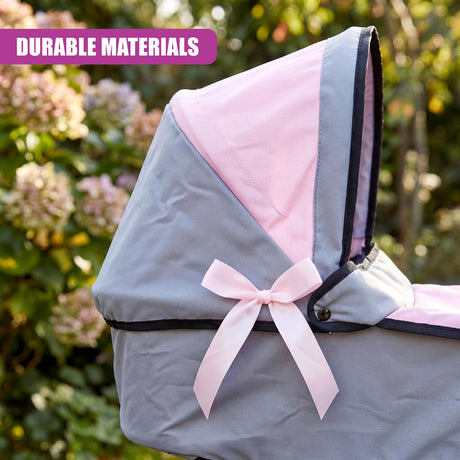 The open canopy of a pink and gray toy pram features a decorative pink ribbon bow.