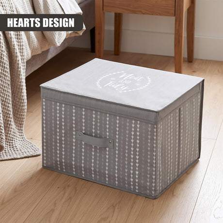 A large gray fabric storage box with a heart pattern and "Neat and Tidy" on the lid, placed on a wooden floor next to a bed