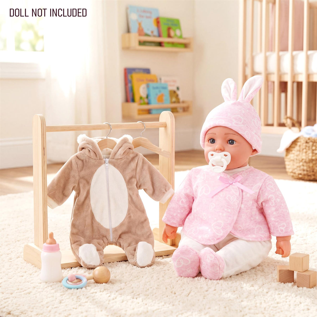 Doll wears pink bunny clothes next to a bear outfit hanging on a small wooden clothes rack.
