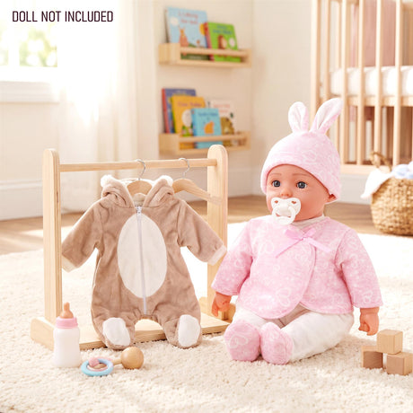 Doll wears pink bunny clothes next to a bear outfit hanging on a small wooden clothes rack.