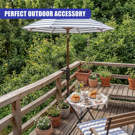 Open striped parasol stands on a wooden deck with potted plants and tableware.
