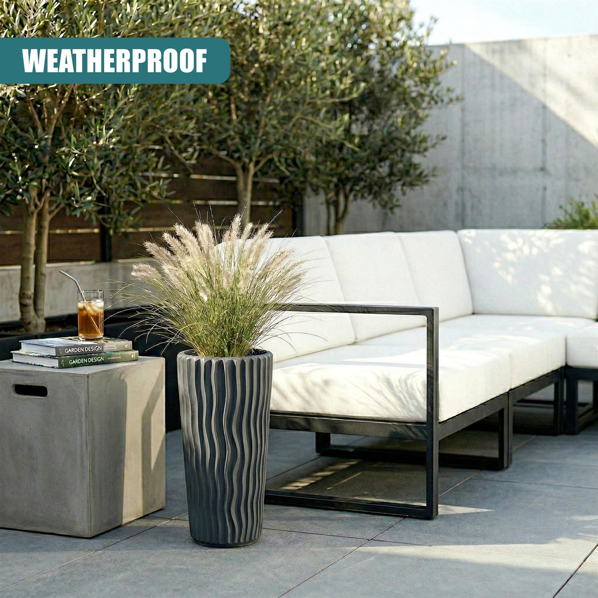 Anthracite striped flower pot holding ornamental grass, placed outdoors next to modern patio furniture.