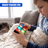 Young boy examining a brightly colored, handheld cube puzzle game while seated on a couch.