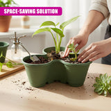 Hands plant small leafy plants into a segmented, deep green, tiered planter filled with soil.