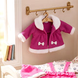 Purple doll coat with white trim and bow displayed on a hanger, alongside other pink clothing accessories.