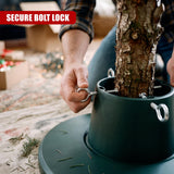 A person's hands tightening a metal bolt on a green adjustable Christmas tree stand holding a real tree trunk