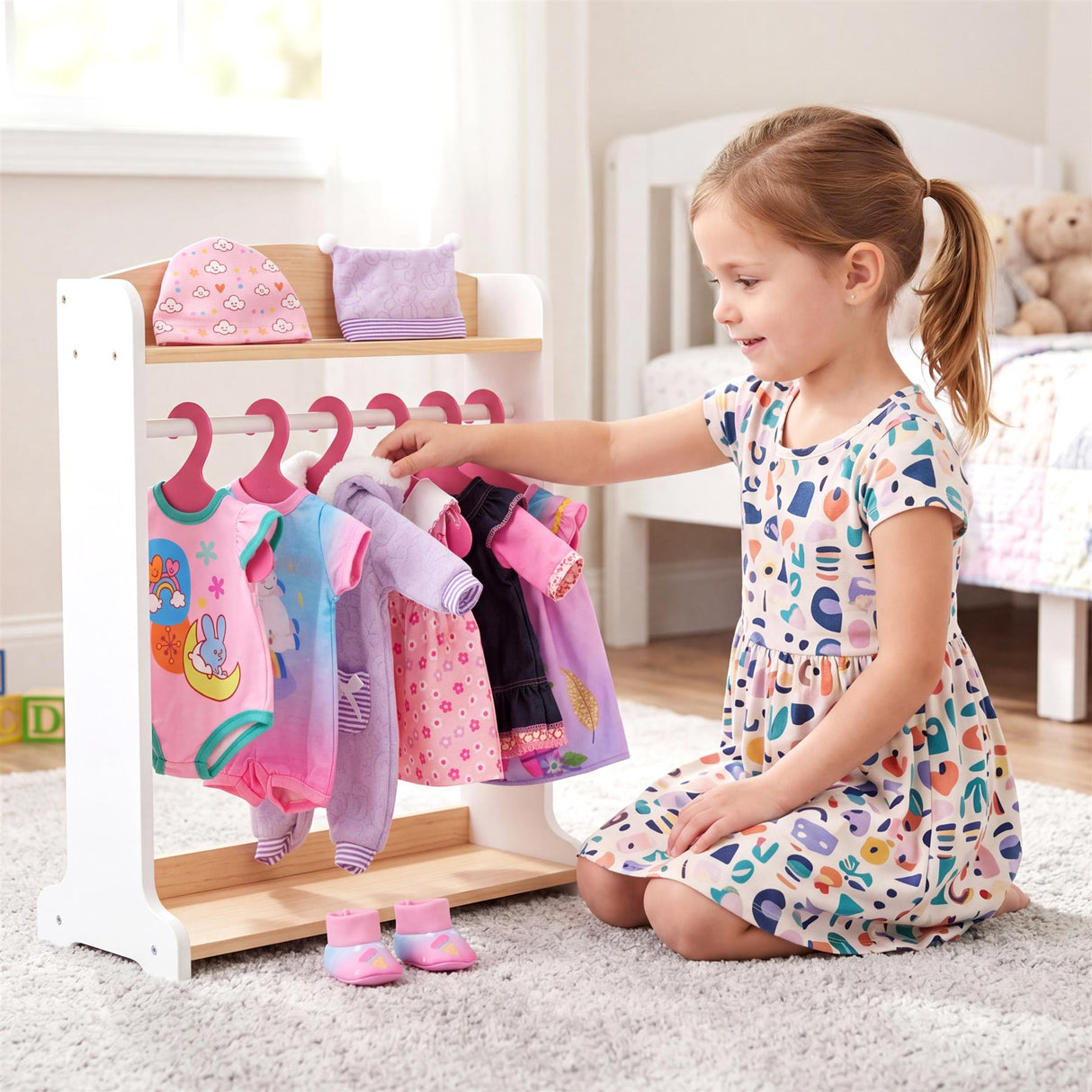 Young girl arranging colorful, patterned clothes on a white display rack.