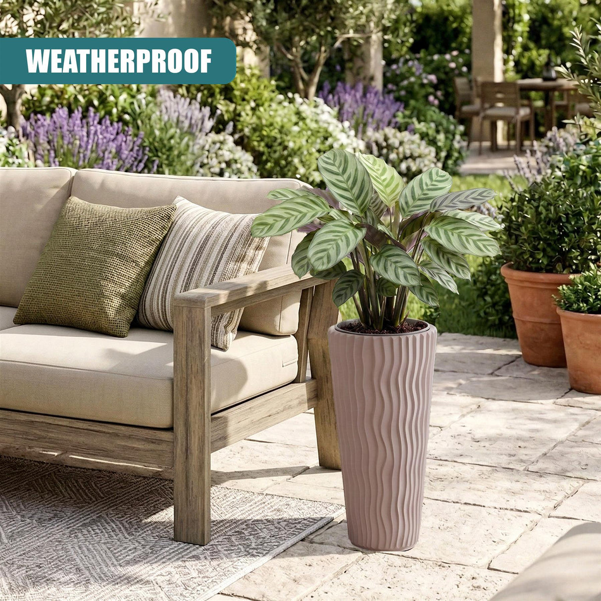 A tall, ribbed, light beige ceramic pot holding a vibrant green houseplant in an outdoor setting.